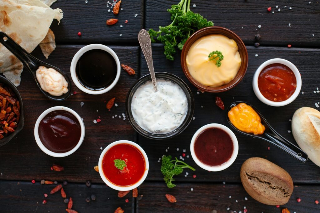 Bowls of barbecue sauces, dips and spices on a dark wooden table